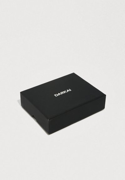 Čierna obdĺžniková krabička s hladkým povrchom, na hornej strane je biely nápis "DARKAI".
