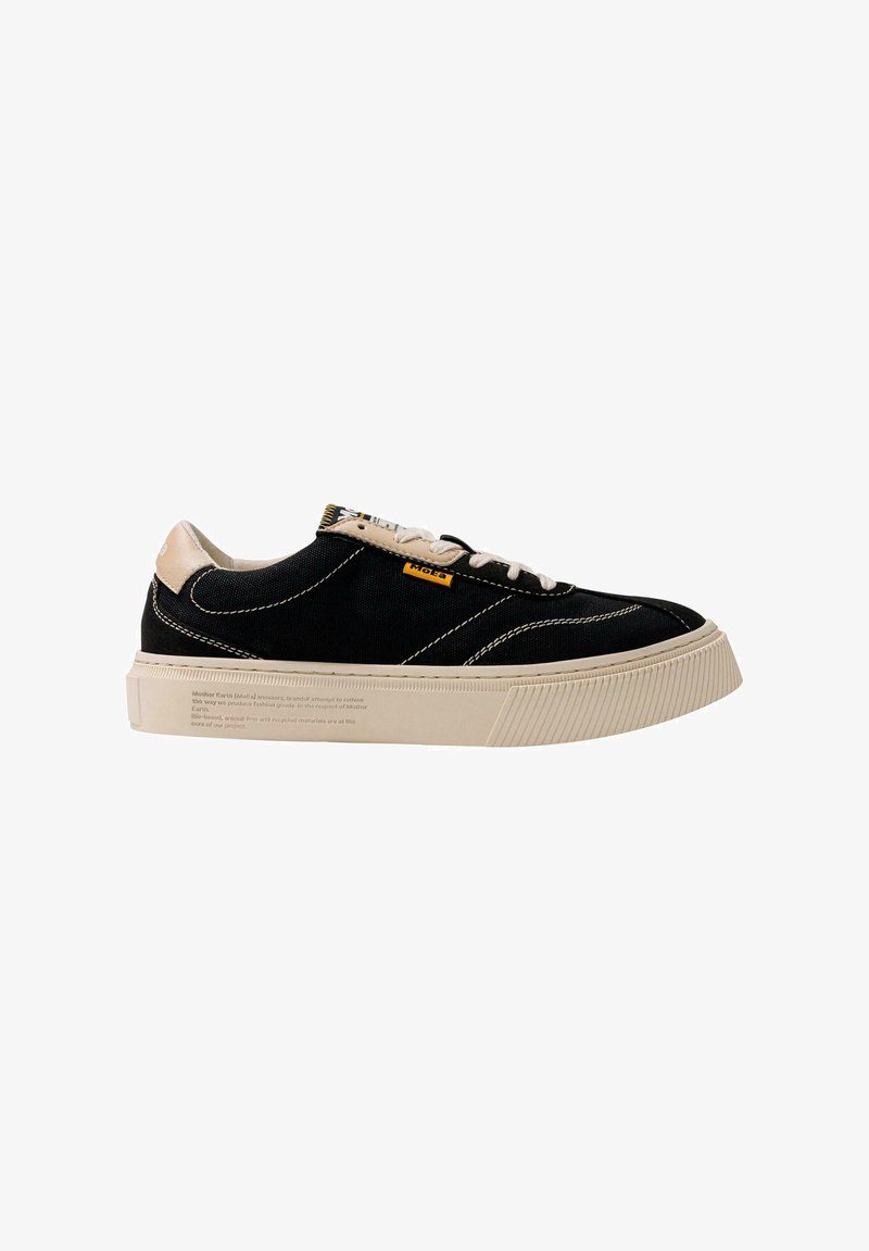 Fekete vászon sportcipők bézs sarokkal, krém színű fűzőkkel és textured gumi talppal. Jellemzője a sárga logó és a látható fehér varrás.