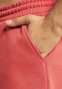Korallgyapjú jogger nadrág gumis derékkal és oldalsó zsebbel. Puha tapintás, keskeny varrás és keskenyített fazon látható.