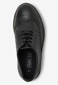 Zwarte leren brogue schoen met decoratieve perforaties en stiksels. Beschikt over een ronde neus en een klassiek vetersluiting ontwerp.