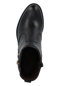 Bottine en cuir noir avec une finition lisse, bout rond, fermeture éclair sur le côté et détail de couture décoratif. Intérieur doublé de tissu marron.