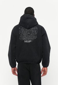Svart hettegenser med avslappet passform, med et grafisk design av bylandskap og tekst på baksiden; laget av myk bomullsblanding.