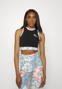 Top curto preto de alças coloridas de padrão; combinado com leggings brancas com desenhos geométricos e abstratos em cores pastel.