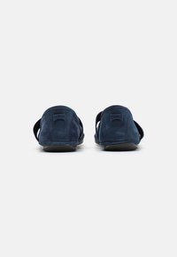 Mörkblå mocka slip-on skor med en slät yta, öppna sidor och en minimalistisk design. Har en diskret Camper-logotyp på hälen.