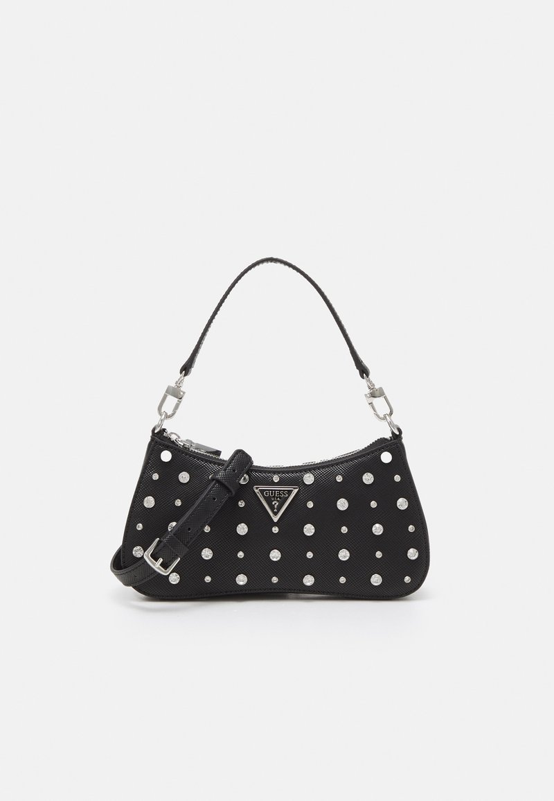 Czarna torebka o subtelnym połysku, ozdobiona srebrnymi ćwiekami, ma zaokrąglony kształt, zamek błyskawiczny, odpinany pasek i plakietkę z logo.