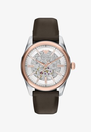 Pánské automatické náramkové hodinky s hnědým koženým páskem, růžově zlatým rámečkem, skeletovým ciferníkem zobrazujícím mechanické ozubené kolečka a růžově zlatými hodinovými značkami a ručičkami.