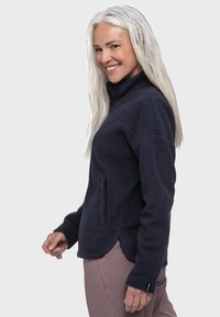 Navy Fleece-Pullover mit hohem Kragen, strukturiertem Außenmaterial, seitlichen Taschen und einem leicht geschwungenen Saum. Weicher Stoff, leichtes Design.