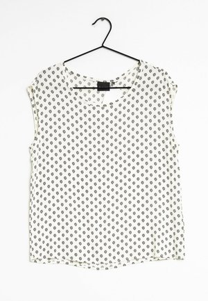 Camicia a maniche corte con scollatura tonda, realizzata in tessuto leggero, con sfondo bianco e piccoli motivi geometrici neri.