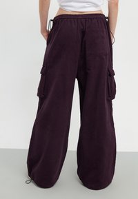 Baggy cordflanellbyxor i djup lila med en mjuk textur, med sidofickor och resårmidja med justerbara dragsko.