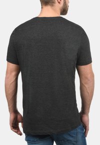 Camiseta de manga corta en gris oscuro con cuello redondo. Confeccionada en una suave tela texturada. La vista trasera muestra un dobladillo recto y costuras mínimas.