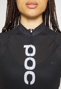 Top atlético negro con cierre de cremallera, que presenta una tela texturizada y un gran diseño numérico blanco en la parte frontal. Logo sutil de Nike en un costado.