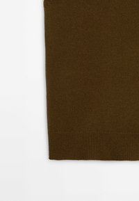 Section de tissu tricoté marron avec ourlet côtelé sur fond blanc, montrant la texture et les détails du tissage.