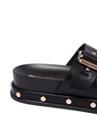 Černé sandály z texturované kůže s širokým páskem a zlatými hřebíčky podél podrážky, s hladkým stélkou a minimalistickým designem.