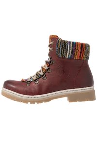 Botín de cuero rojo con puño de punto multicolor, parte delantera con cordones, herrajes plateados y detalle de costura blanca en la suela.