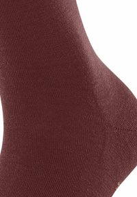 Nahaufnahme einer braunen Stricksocke, die die detaillierte Gewebestruktur und die Nähte im Fersenbereich zeigt.