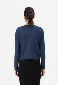 Navy knitted sweater with ribbed texture, long sleeves, and rounded neckline, cropped style, shown from the back against a white background.