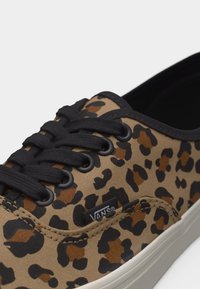 Gros plan sur une basket Vans à imprimé léopard avec des lacets noirs et une semelle en caoutchouc blanche.