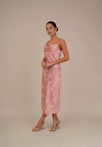 Vestido floral de cetim rosa com alças finas, comprimento até metade da panturrilha, textura suave, adornado com um delicado padrão de flores, combinado com sapatos de salto com tiras.