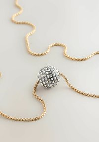 Goldene Kettenhalskette mit einem kugelförmigen Anhänger, der mit klaren Strasssteinen bedeckt ist und einen strukturierten, funkelnden Effekt erzeugt.