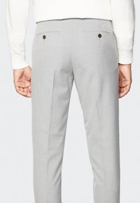 Szare dopasowane spodnie o gładkim wykończeniu, z dwiema tylnymi kieszeniami z brązowymi guzikami oraz prostym krojem.