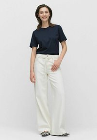 Marinblå bomullströja i kombination med högmidjade, vida vita byxor med dragstring. Zebramönstrade ballerinas fulländar looken.