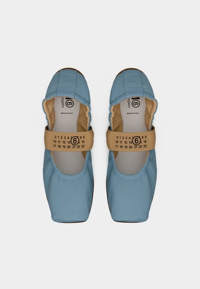 Ζευγάρι ανοιχτό μπλε παπούτσια χωρίς κορδόνια με ταμπά ελαστικές λουρίδες που φέρουν μαύρο αριθμητικό τύπωμα, σε θέα από πάνω σε λευκό φόντο.