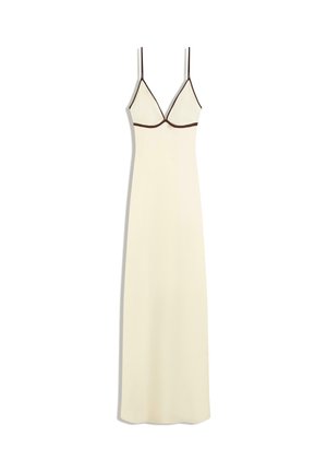 Dlhé krémové šaty na ramienka s tenkými čiernymi ramienkami a čiernym lemom pod prsiami, priliehavé hore a plynulo padajúce až k lemu.
