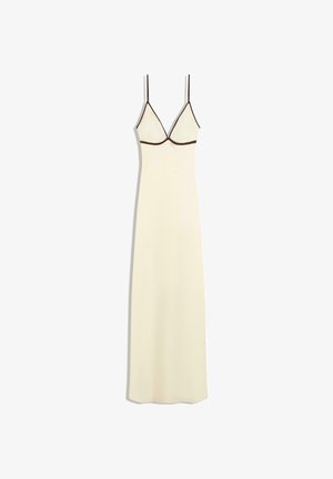 Longue robe nuisette crème avec fines bretelles noires et bordure noire sous la poitrine, ajustée sur le haut et s'étendant droite jusqu'à l'ourlet.