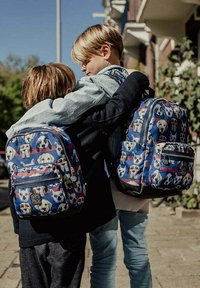 Twee rugzakken zijn voorzien van een blauwe stof versierd met hondpatronen, rode strepen en ritsen. Eén rugzak heeft een logo-opdruk die goed zichtbaar is.