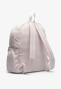 Sac à dos rose clair à rayures avec tissu texturé, bretelles ajustables et poche latérale froncée. Forme arrondie avec une boucle de suspension en haut.