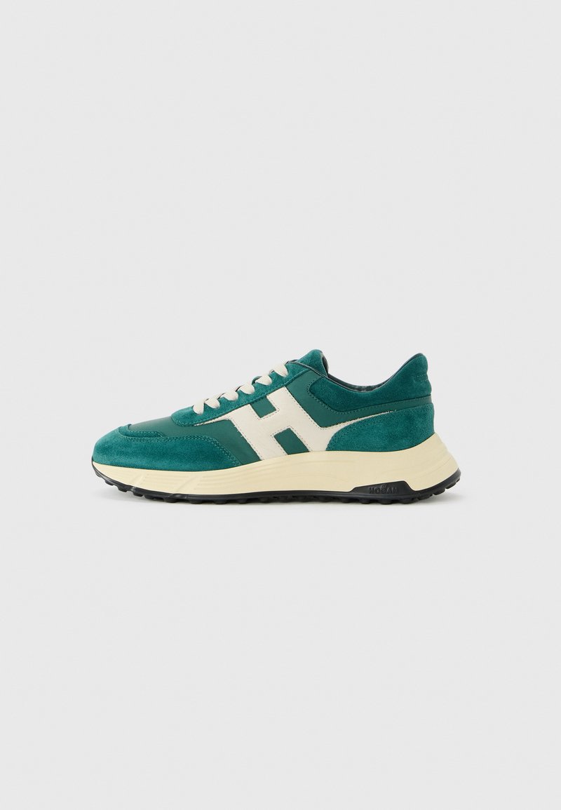 Green suede and leather sneaker with beige "H" logo, white laces, and thick beige sole with black tread on white background.