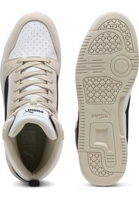 Baskets montantes Puma en blanc et beige avec des accents noirs. Présentent du daim perforé, une semelle en caoutchouc texturé et un col rembourré pour le confort.