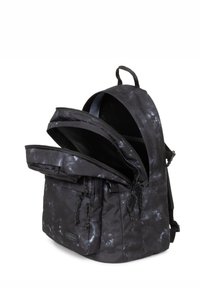 Svart ryggsäck med flera zip-fack och justerbara remmar. Strukturerad tyg med ett subtilt prickigt mönster.