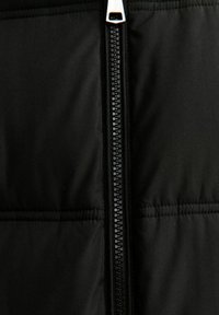 Giacca a vento nera con chiusura centrale a zip, texture a rombi e due cuciture orizzontali per un ulteriore dettaglio di design.