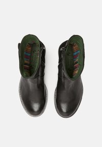 Botas de tobillo de cuero negro con un acabado suave, cierre de cremallera, forro verde y plantilla colorida a rayas. Diseño de punta redonda y tacón bajo.