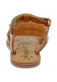 Bruine leren sandaal met gouden accenten, voorzien van een open tenen, verstelbare band en een bloemenpatroon op de binnenzool. Platte zool.