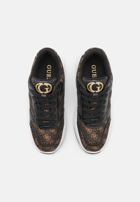 Sneakers neri con accenti a motivo marrone, dotati di una tomaia in pelle nera lucida, chiusura con lacci e un dettaglio del logo dorato sul lato.