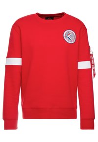 Felpa rossa con maniche lunghe, strisce orizzontali bianche sulle maniche, colletto rotondo e logo di Apollo 12 sul petto. Presenta una tasca con zip.