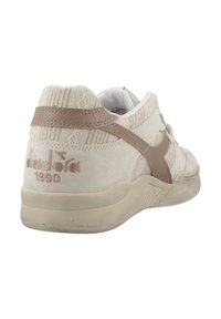 Cremfarbene Wildledersneaker mit beigefarbenen Lederakzenten, ausgestattet mit einem strukturierten Design, eingeprägtem Logo und einer Gummisohle. Subtle Farbkontrast in den Details.