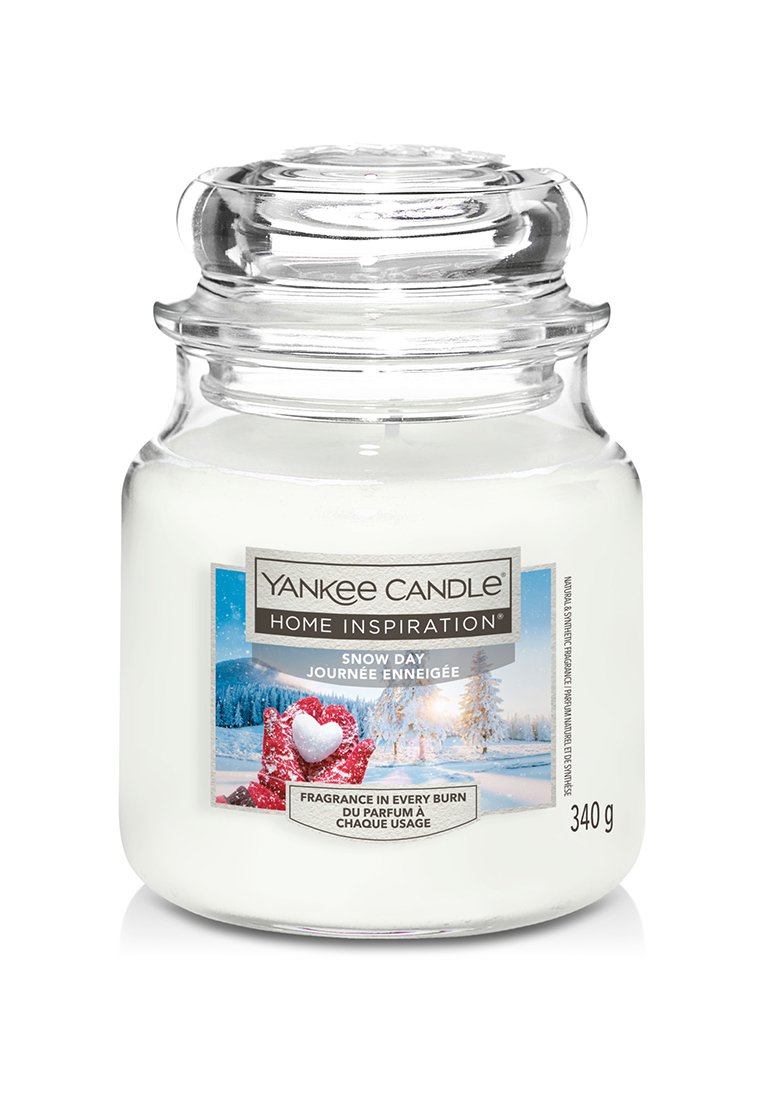 Barattolo di candela in vetro trasparente con interno di cera bianca. L'etichetta presenta un paesaggio innevato con accenti rossi. Coperchio incluso. Peso: 340 g.