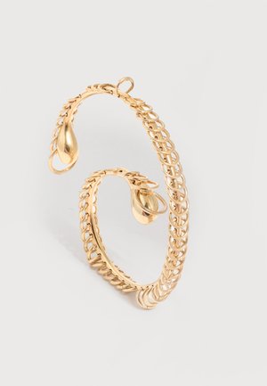 Otwarta złota kolczyk koło z wzorem z ogniw łańcucha i końcówkami w kształcie łezki na jasnym tle.