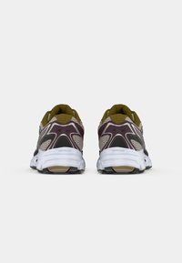 Basketball chaussures avec une tige en mesh de couleur violet foncé et beige, dotées de semelles blanches et d'accents noirs. Comprend des détails texturés et une structure de soutien.