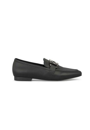 Schwarze Leder-Slipper mit spitzem Zehenbereich und einer dekorativen silbernen Schnalle am Vorderblatt. Flache Sohle mit minimalem Profil. Glatte Textur.