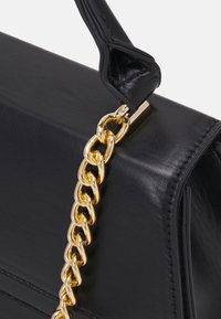 Black leather handbag with a structured design, featuring a gold chain strap and smooth texture. Includes a flap closure and minimal stitching.