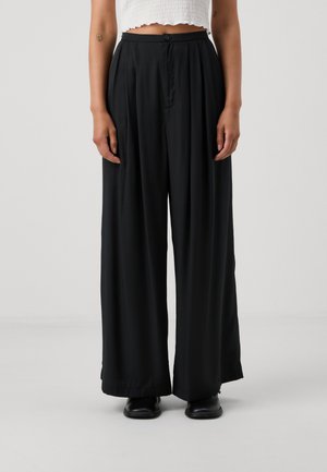 Black wide-leg trousers made of smooth fabric, featuring a button closure and front pleats, with a relaxed fit that drapes elegantly.