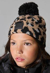 Knit beanie kuosi leopard dengan pom-pom hitam di atas, dilengkapi label hitam persegi panjang dengan teks di depan. Material campuran wol yang hangat.