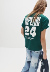 Zelena prevelika majica s kratkimi rokavi z belim napisom "MADE FOR THE CLUB" in številko "24" na hrbtni strani. Enostaven dizajn, mehak material, krojen ovratnik.