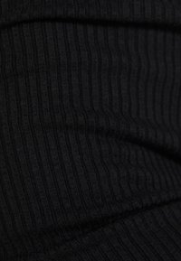 Černá žebrovaná látka s vertikálními pruhy, která se vyznačuje jemnou texturou a mírným leskem, charakteristická pro elastický design oděvu.