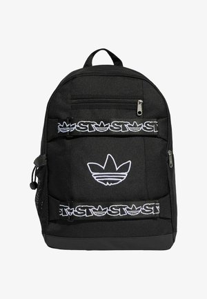 Czarny plecak z białym logo Adidas trefoil i paskami marki Stussy, wyposażony w przednie i boczne kieszenie na zamek oraz boczną kieszeń z siateczki.