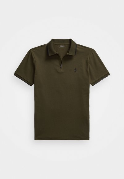 Olivová poloshirt s krátkym rukávom, zipsom v oblasti krku, rebrovaným golierom a jemnými námorníckymi akcentmi. Má vyšívané logo na ľavej hrudi.